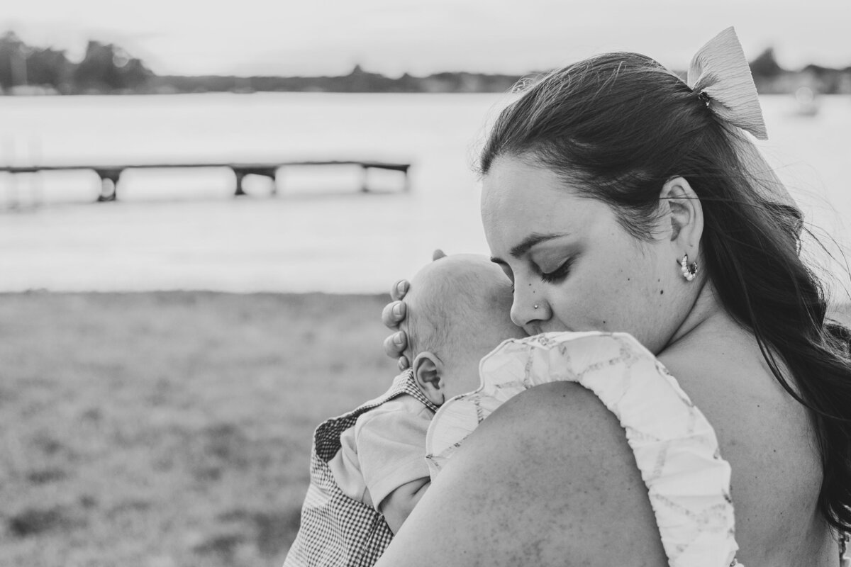 A parent holds their newborn tight on the beach in an endearing moment.