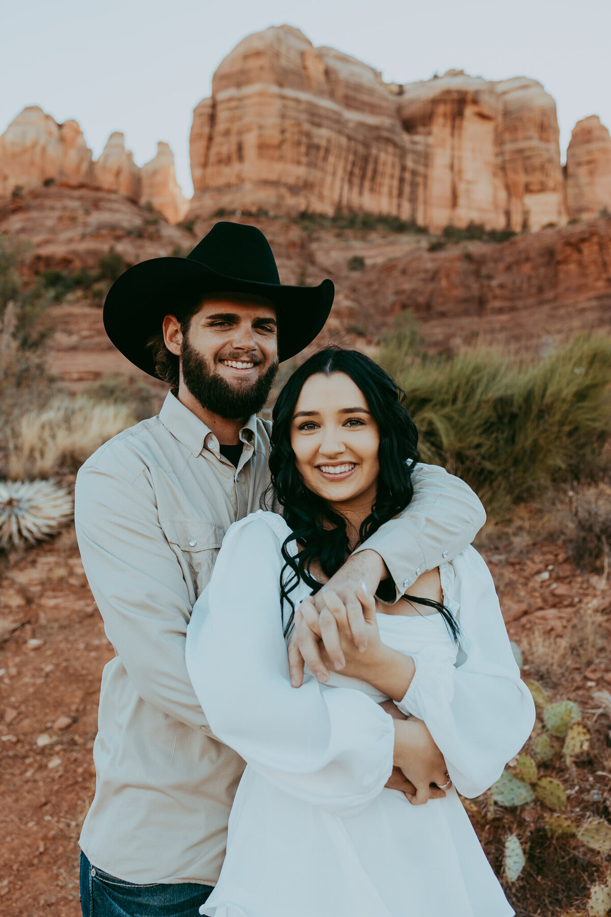 couple embraces with cathedral rock in background