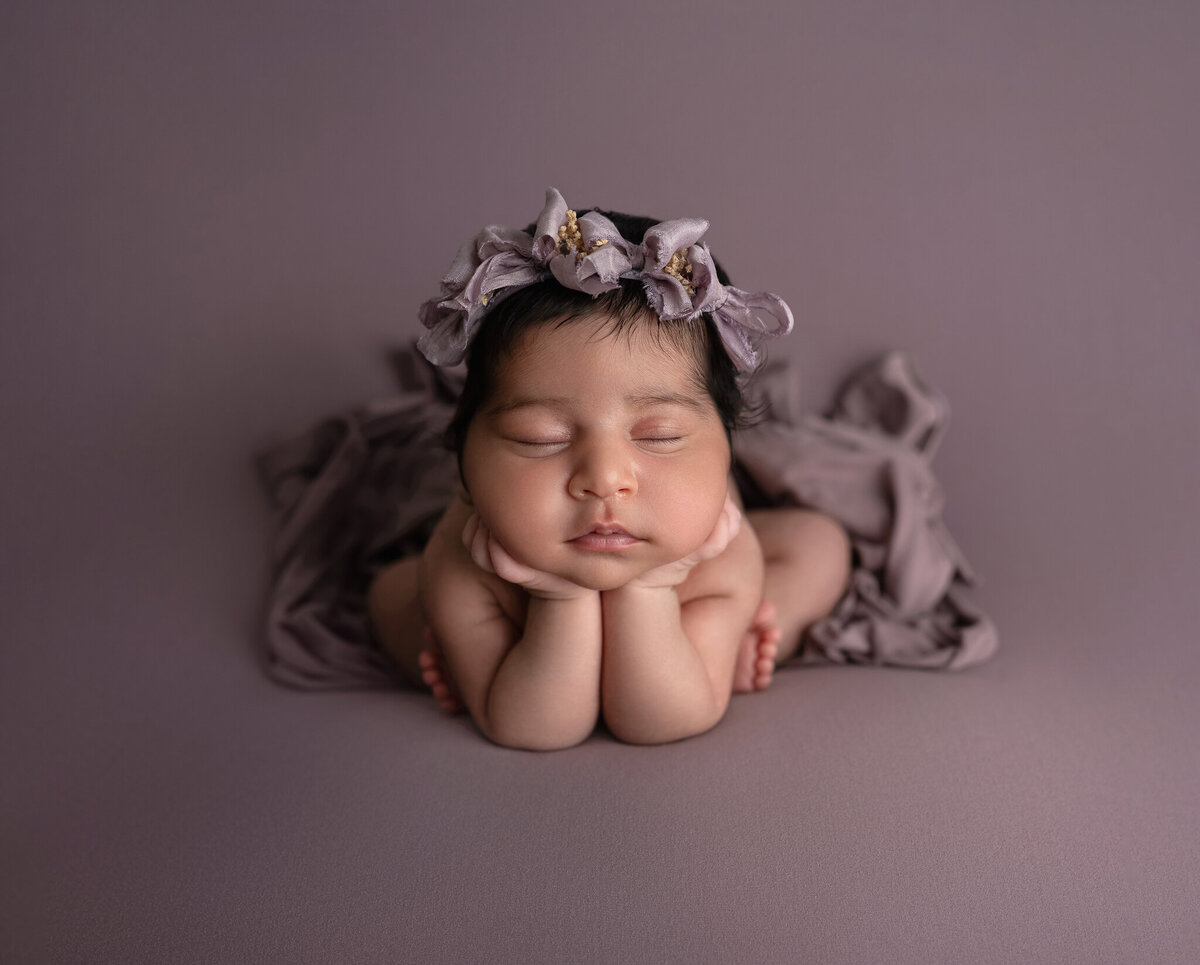 Baby girl in froggy pose with lavender floral headband on soft mauve backdrop | Studio newborn photography in Westlake and Austin, TX