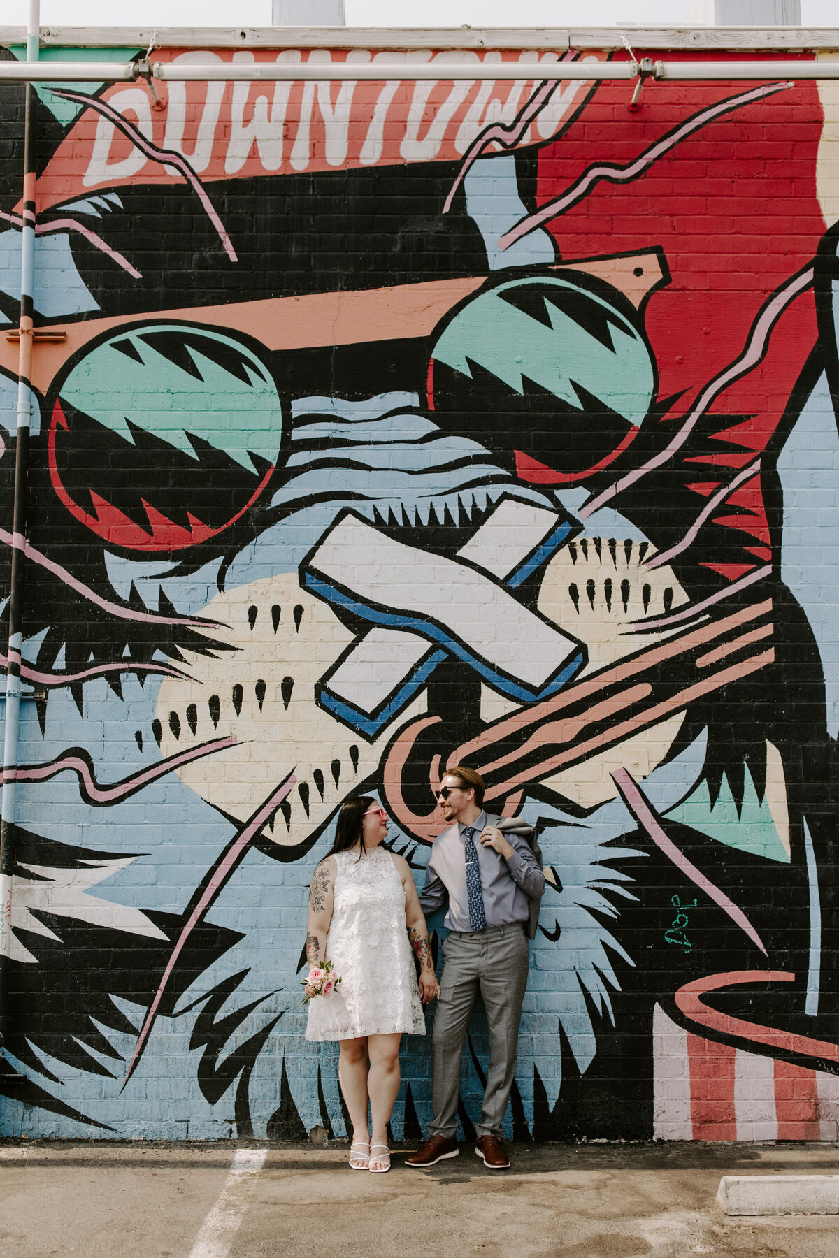 Two partners look at each other in front of street art in Downtown Las Vegas.