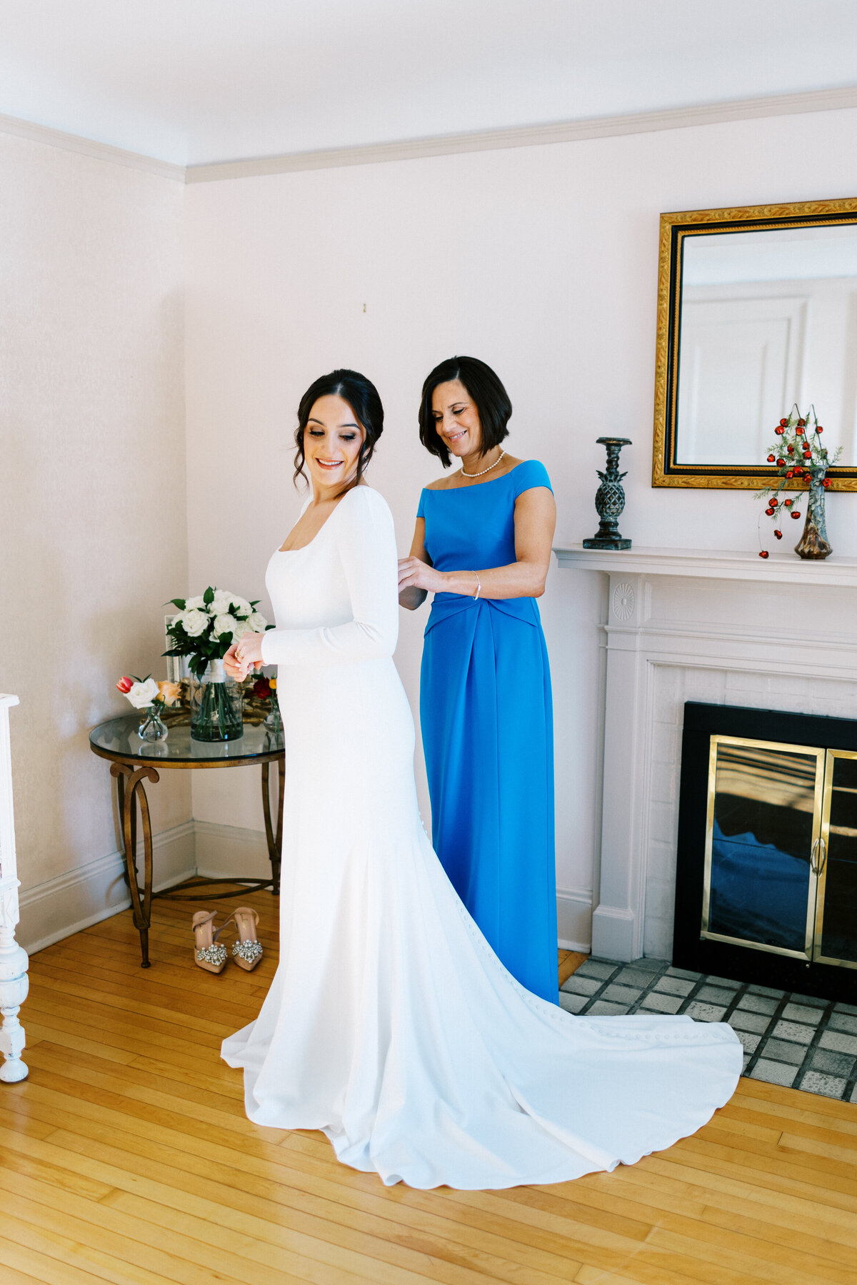 mom helping the bride with her dress