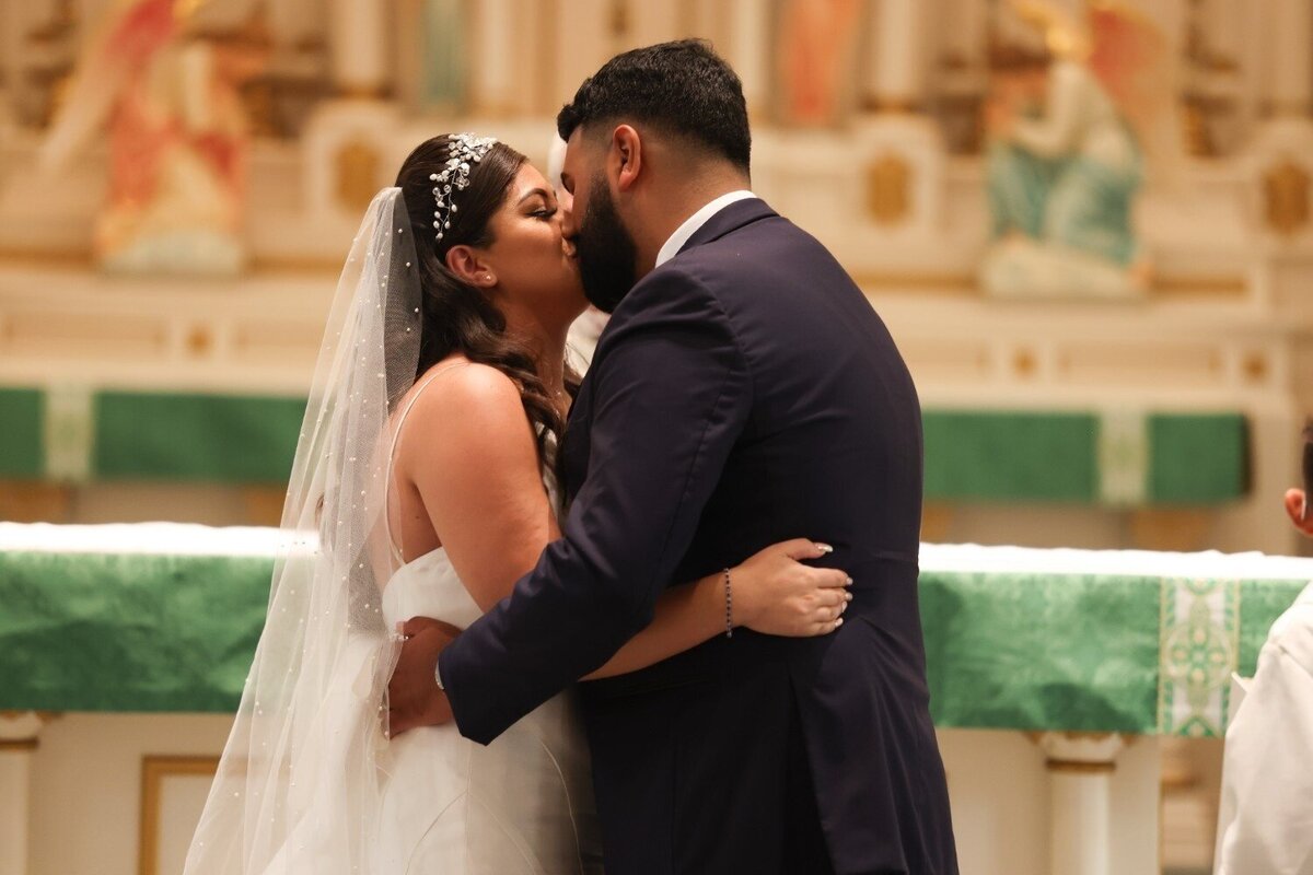 Bride and groom share their first kiss at the altar