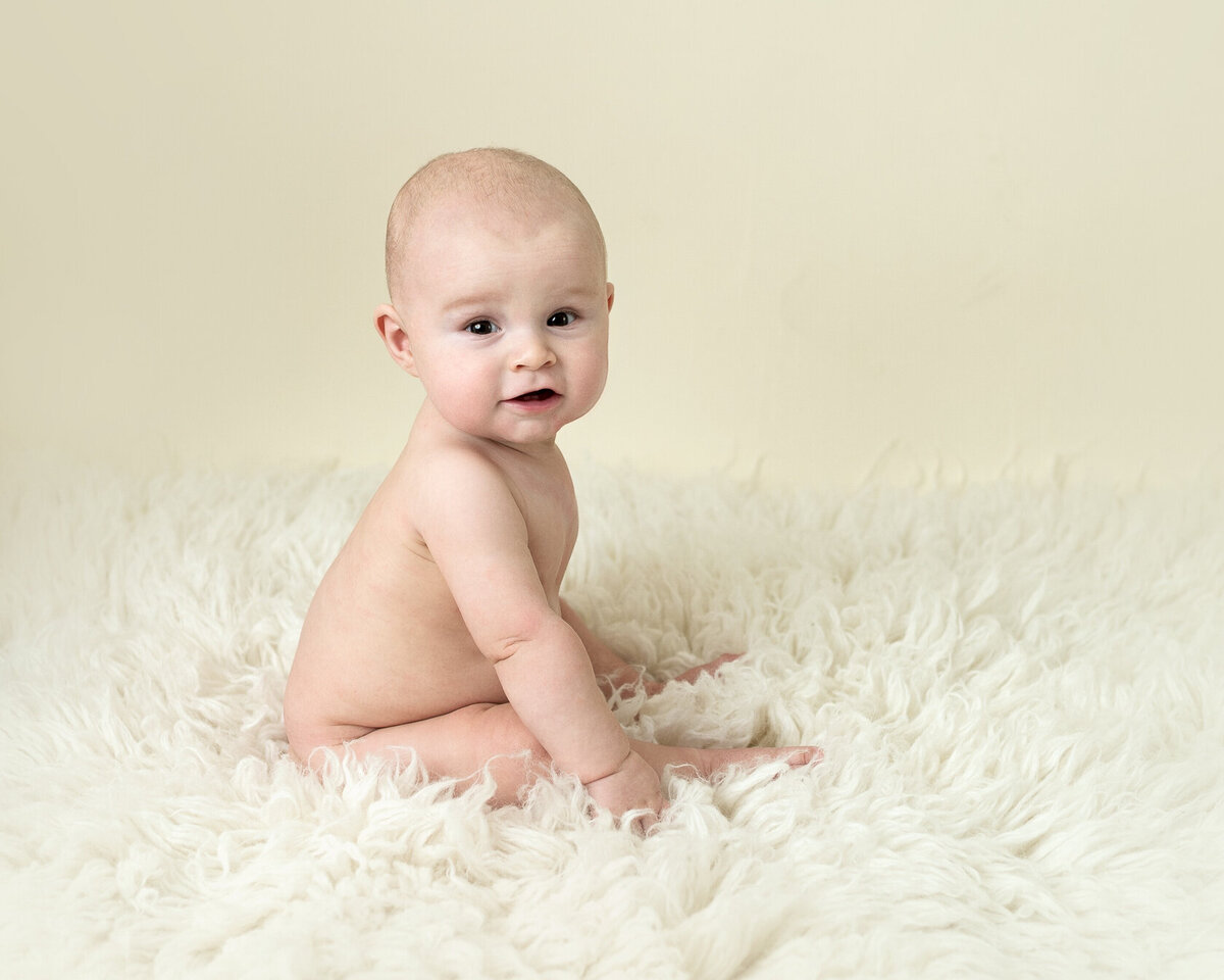 Sitting baby in cream Furry background