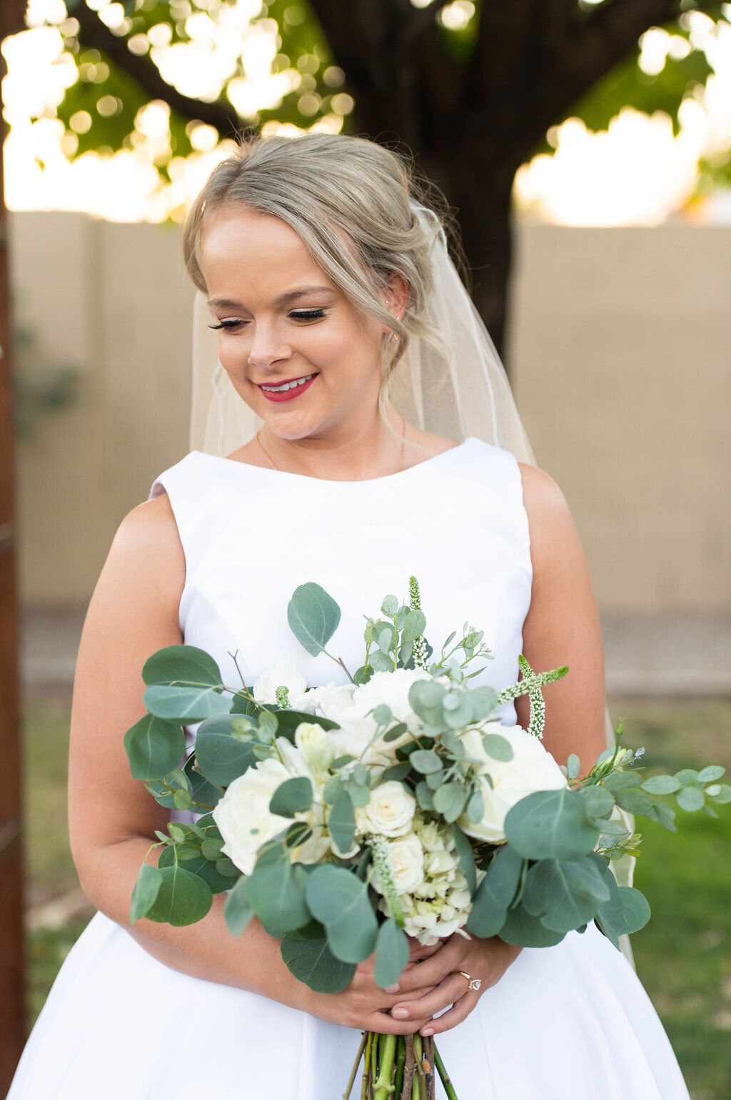 A bride holding a green and white wedding bouquet.