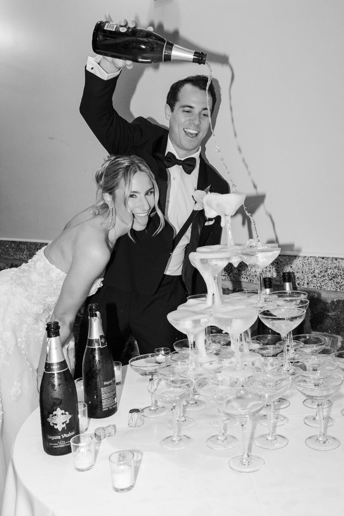 Black and white photo of a bride and groom pouring a champagne tower at Tappan Hill Mansion by Hudson Valley wedding photographers