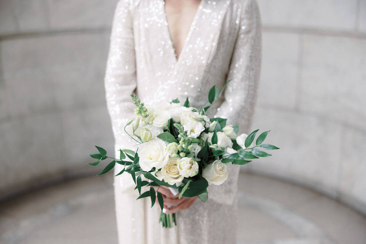 Close-up shot of the white flower bouquet held by the bride inside the New York Public Library, NYC. Image by Jenny Fu Studio