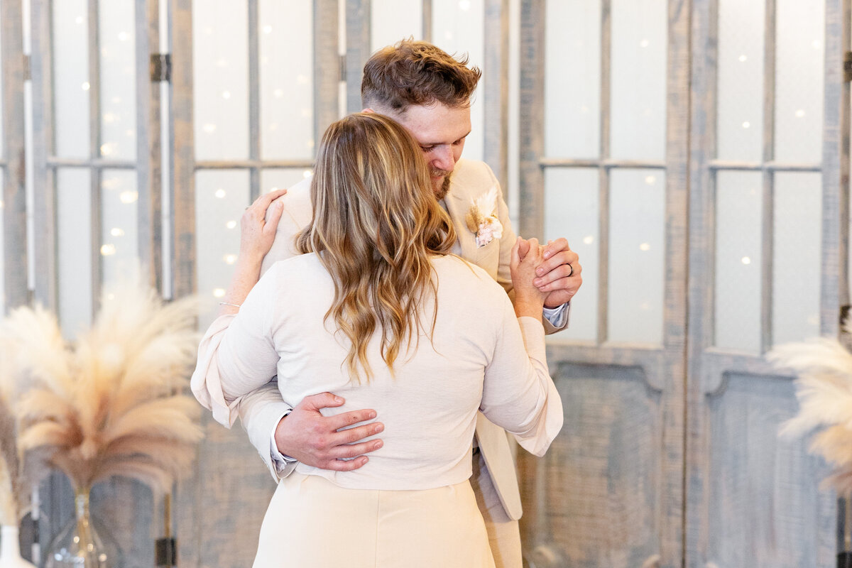 The groom shares a touching dance with his mother, both embracing in a sweet wedding moment.