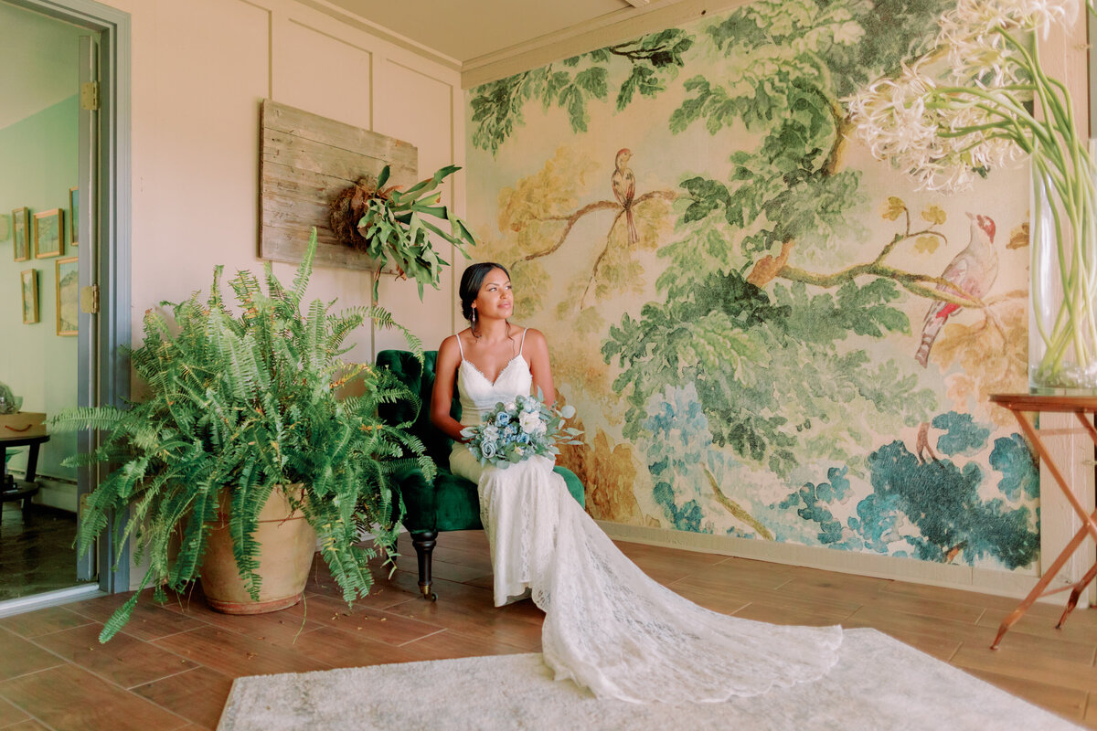a person in a wedding dress sitting down with greenery surrounding them 
