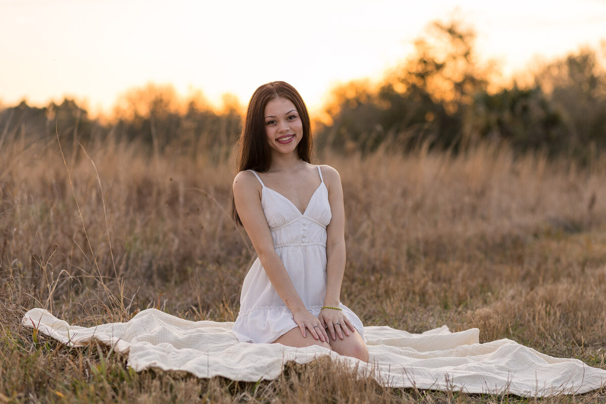 Senior photo of girl sitting on a blanket in a field