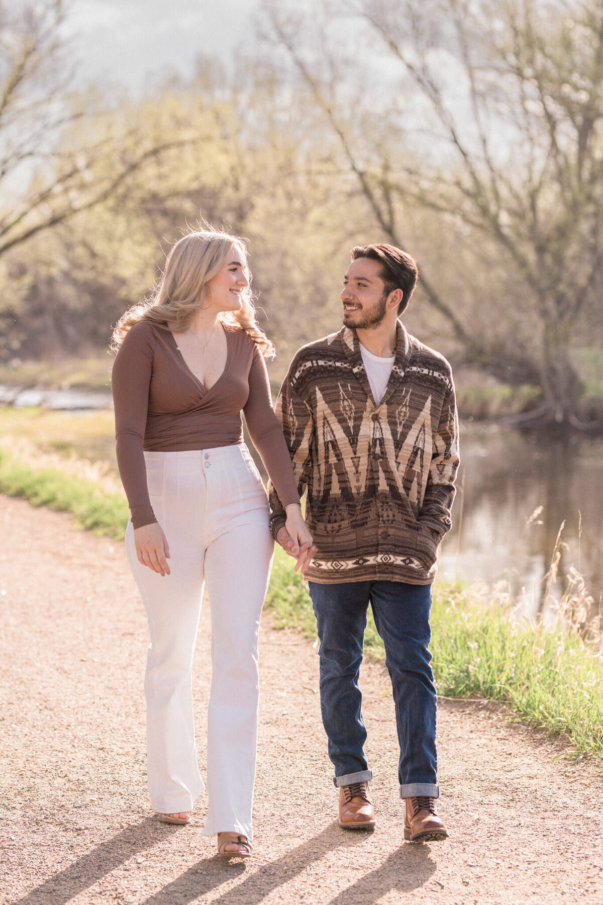 An engaged couple walk beside Boulder Creek during their Engagement Photography session.