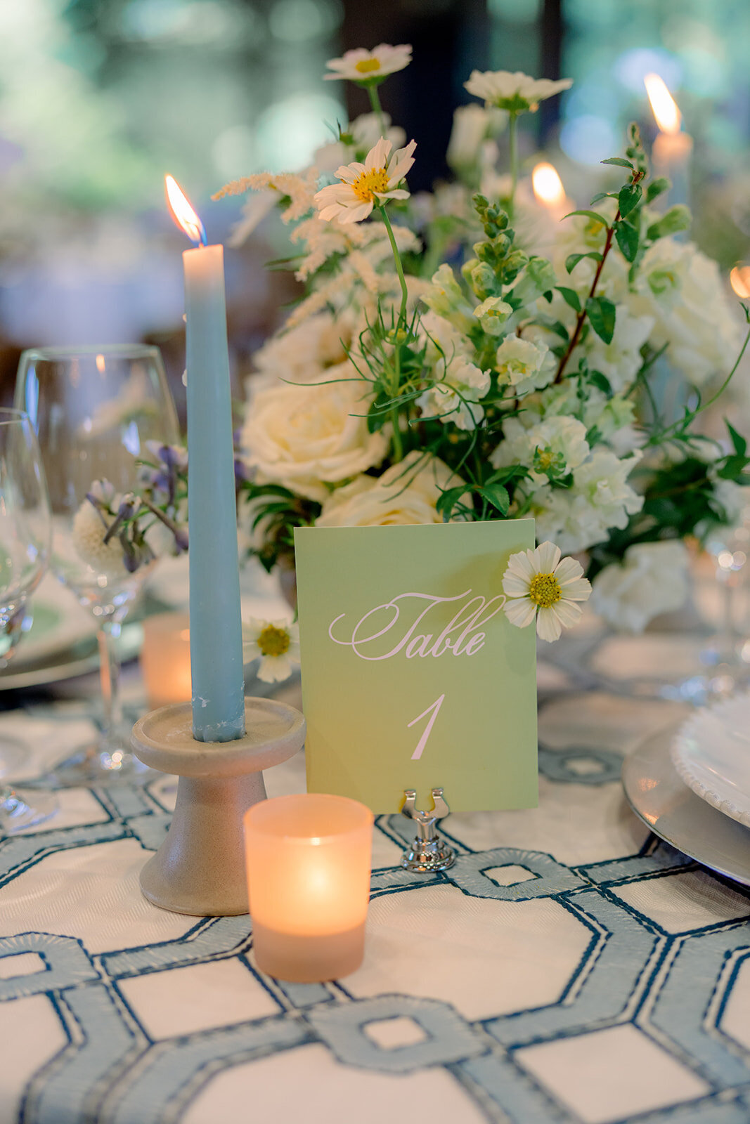 Toile patterned blue linen with candles and delicate florals at elegant wedding dinner setup.