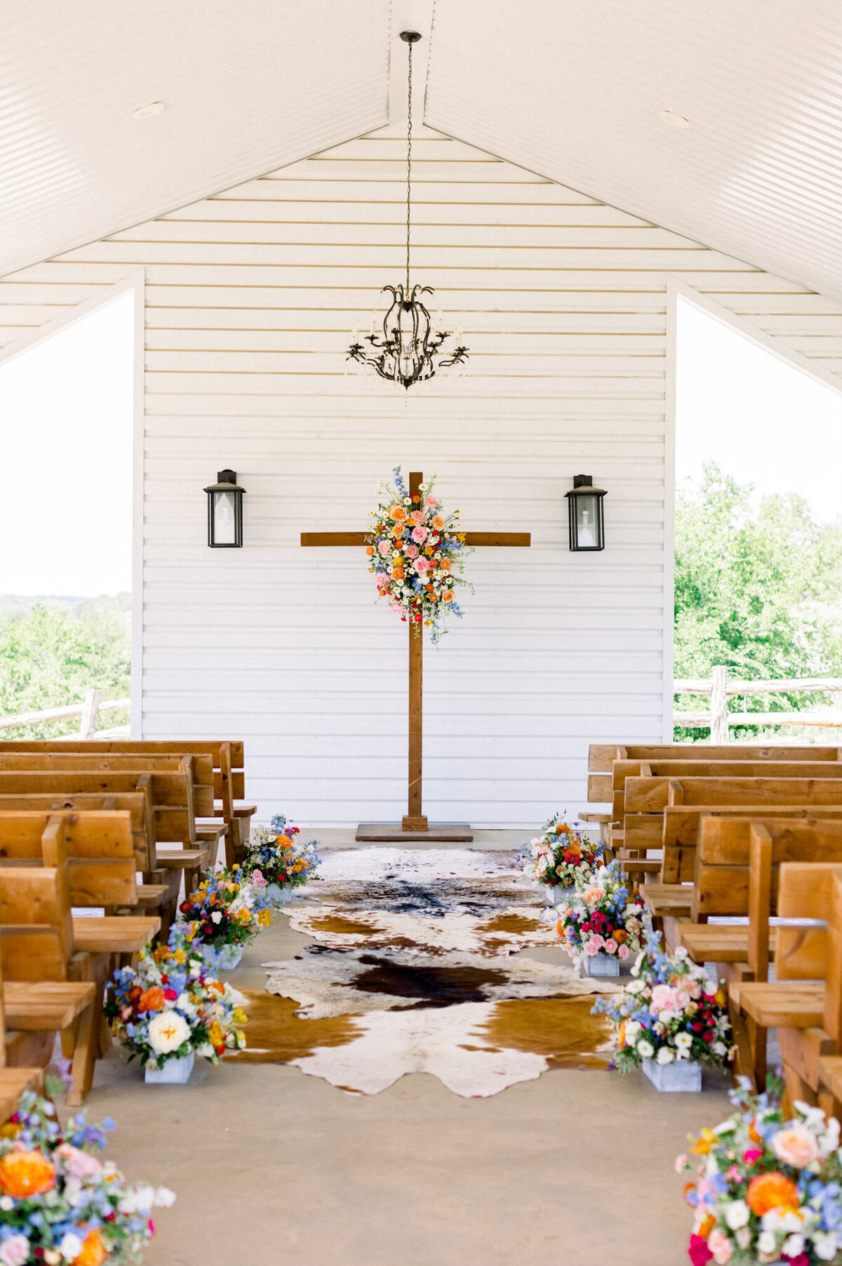 A whimsical ceremony pathway lined with elegant flowers and cowhide rugs