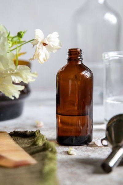 Natural light editorial photography in Richmond Virginia of amber skincare bottle styled for eco beauty and apothecary brands.