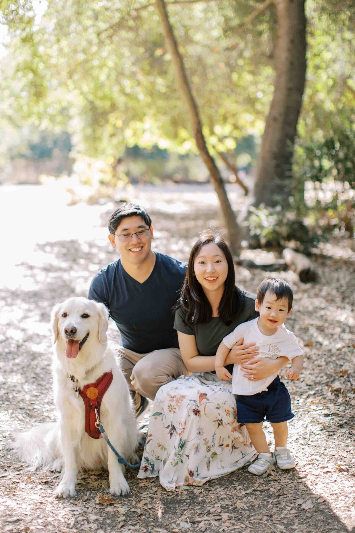 family of 3 smiling with their golden retriever