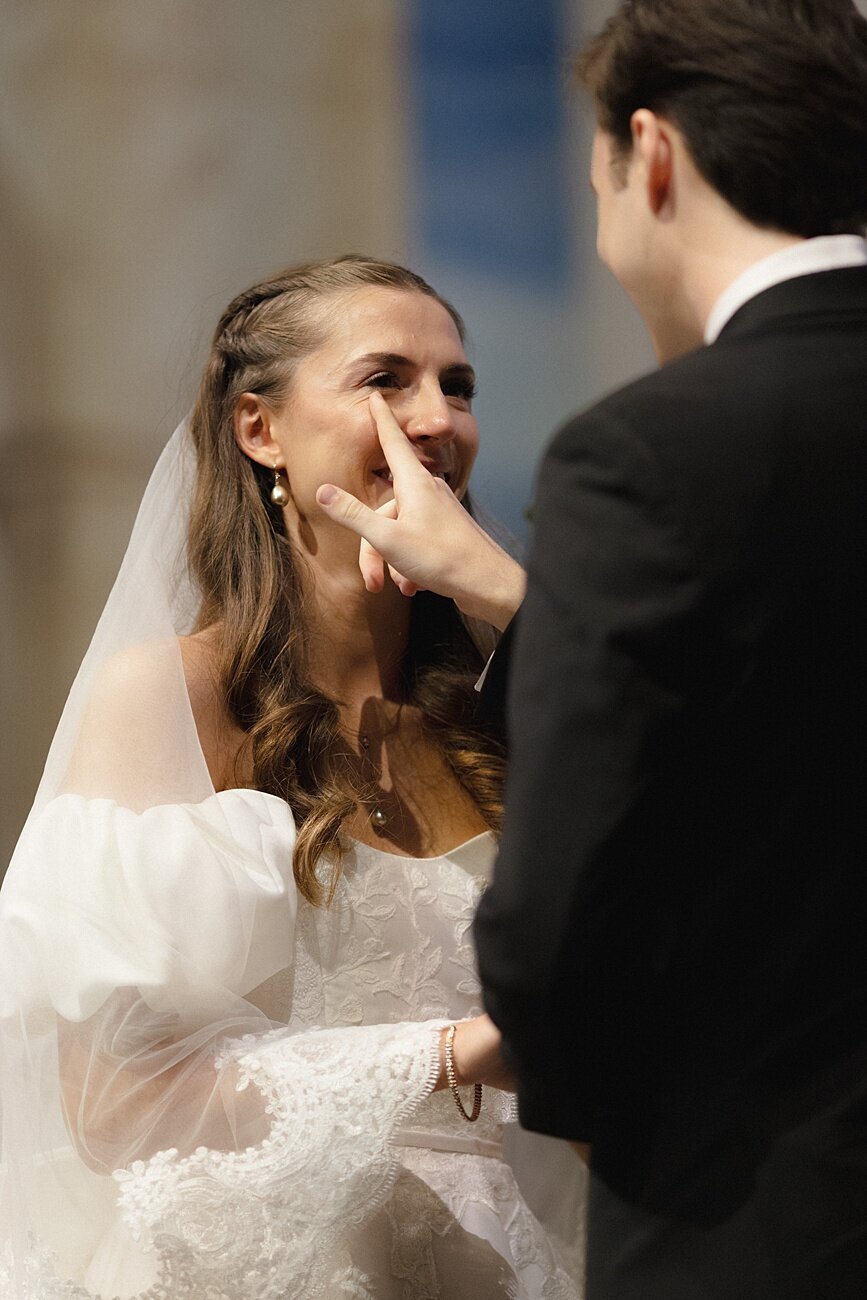 groom wiping tear from bride's eye during the ceremony vows