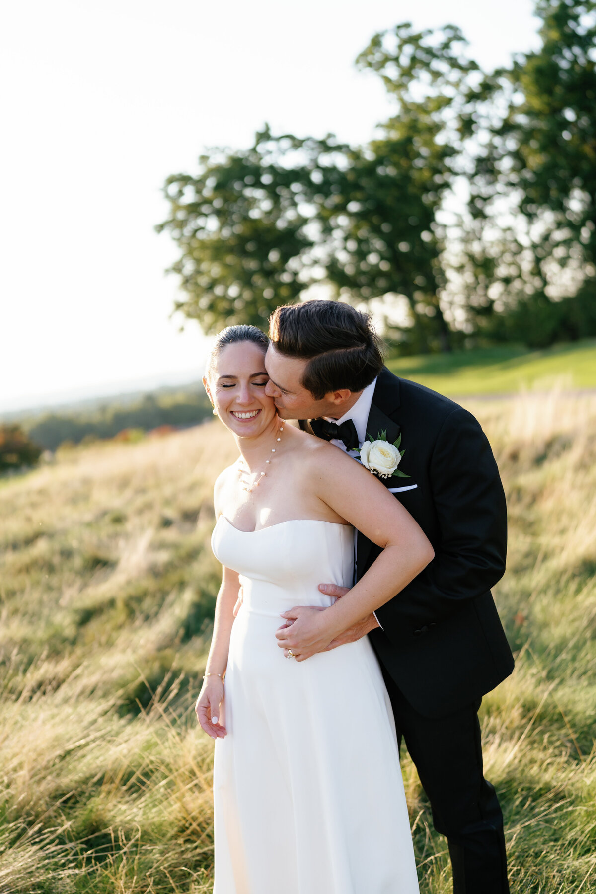 Groom kissing the bride's cheek during sunset photos on the gold course of Arcola Country Club captured by Brenna Marie Photography 