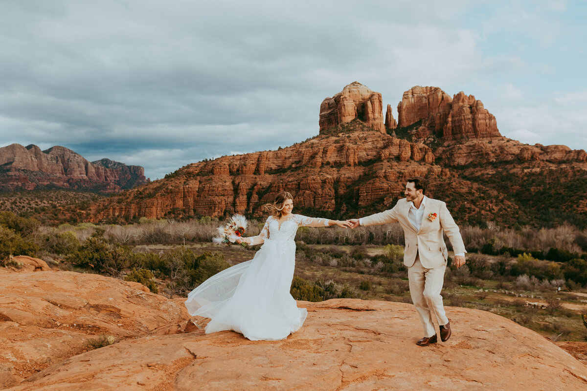 couple laughs as they walk in sedona landscape in bridal attire