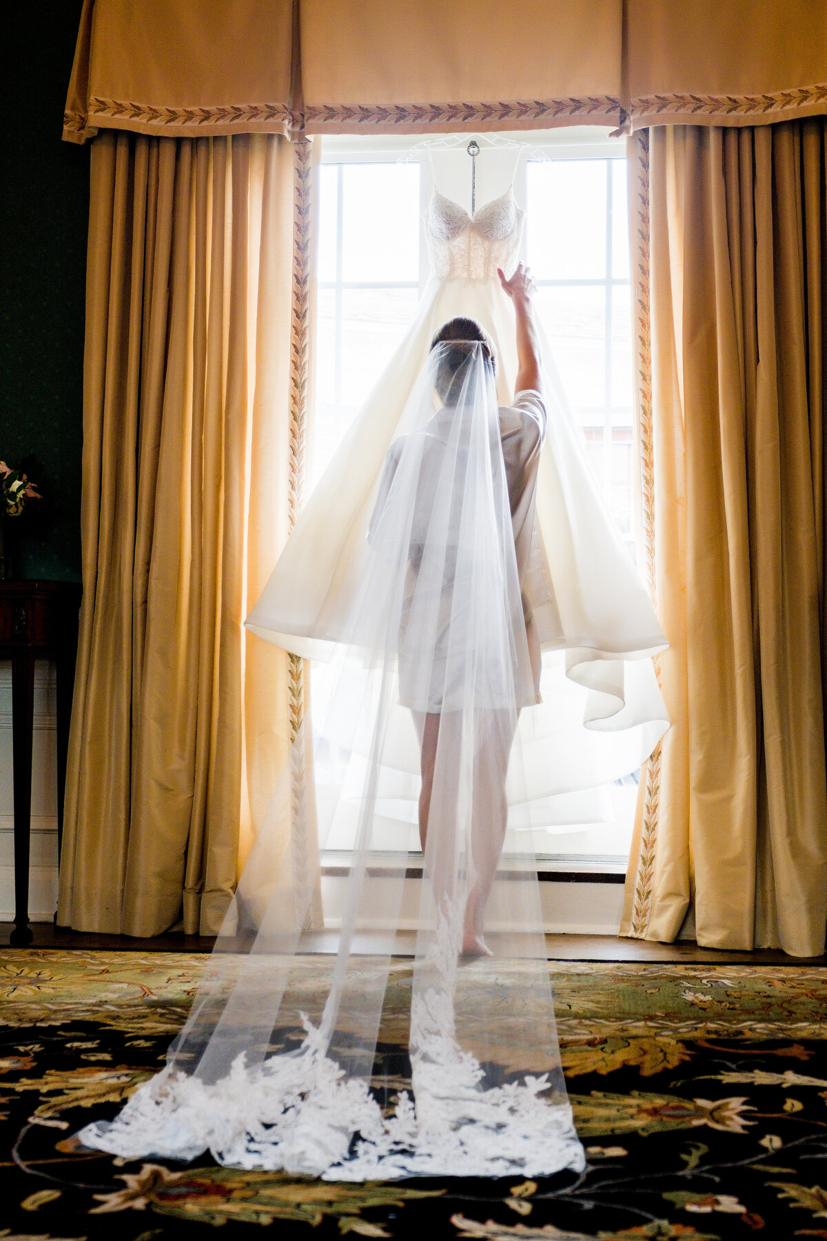 bride reaching for wedding dress in the bridal suite at fox chapel golf club