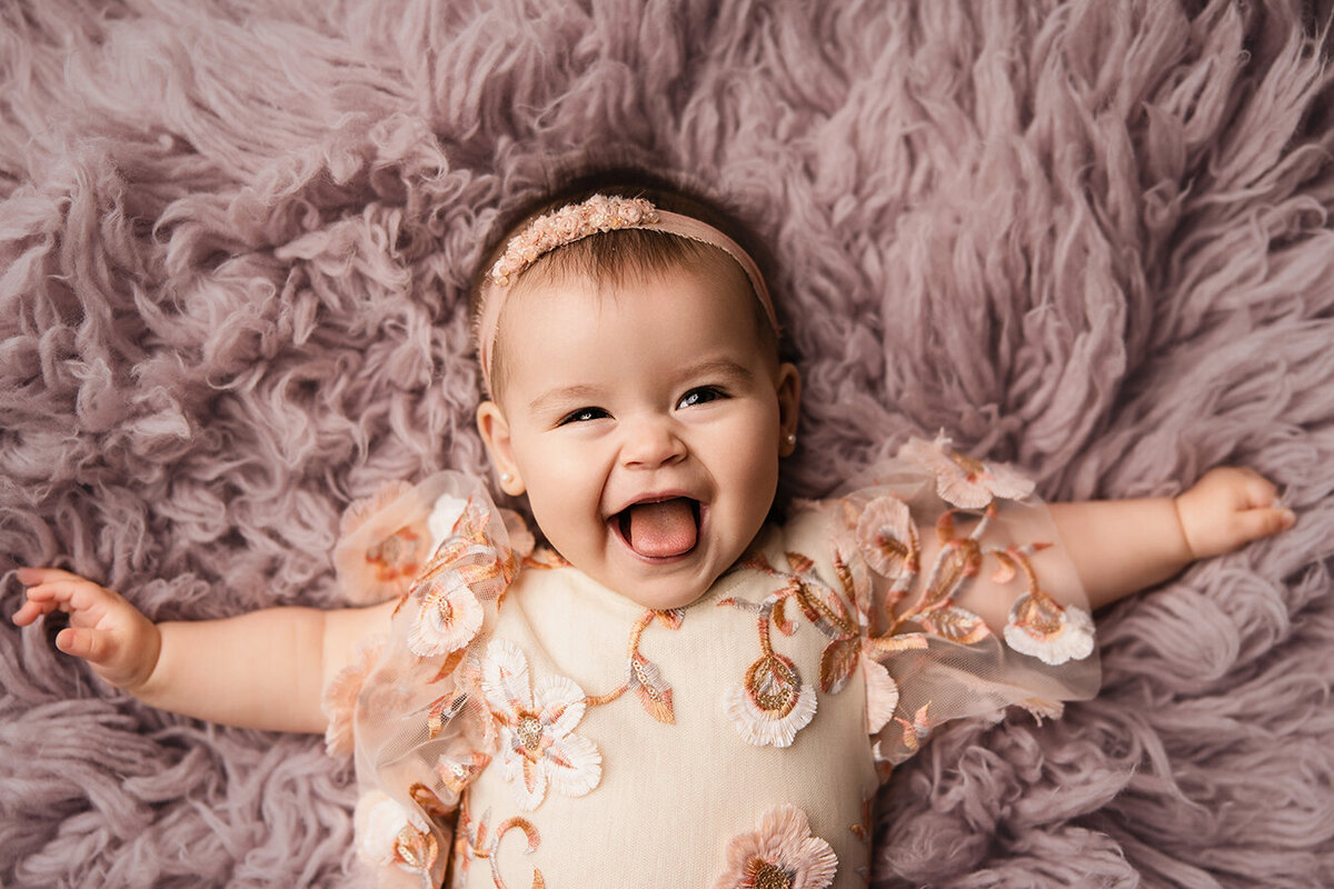 Beautiful baby girl laying on a purple rug in Fort Collins, CO