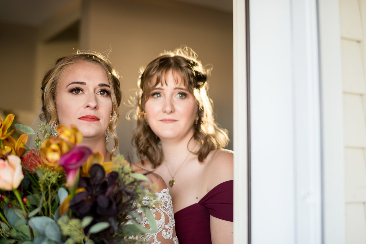 bride and her friend waiting to come out of house and walk down aisle