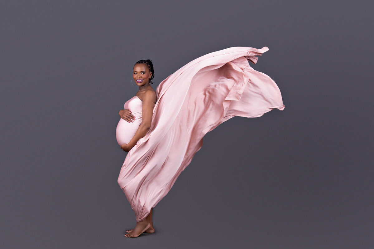 Pregnant mom sitting gracefully in pink flowy gown.