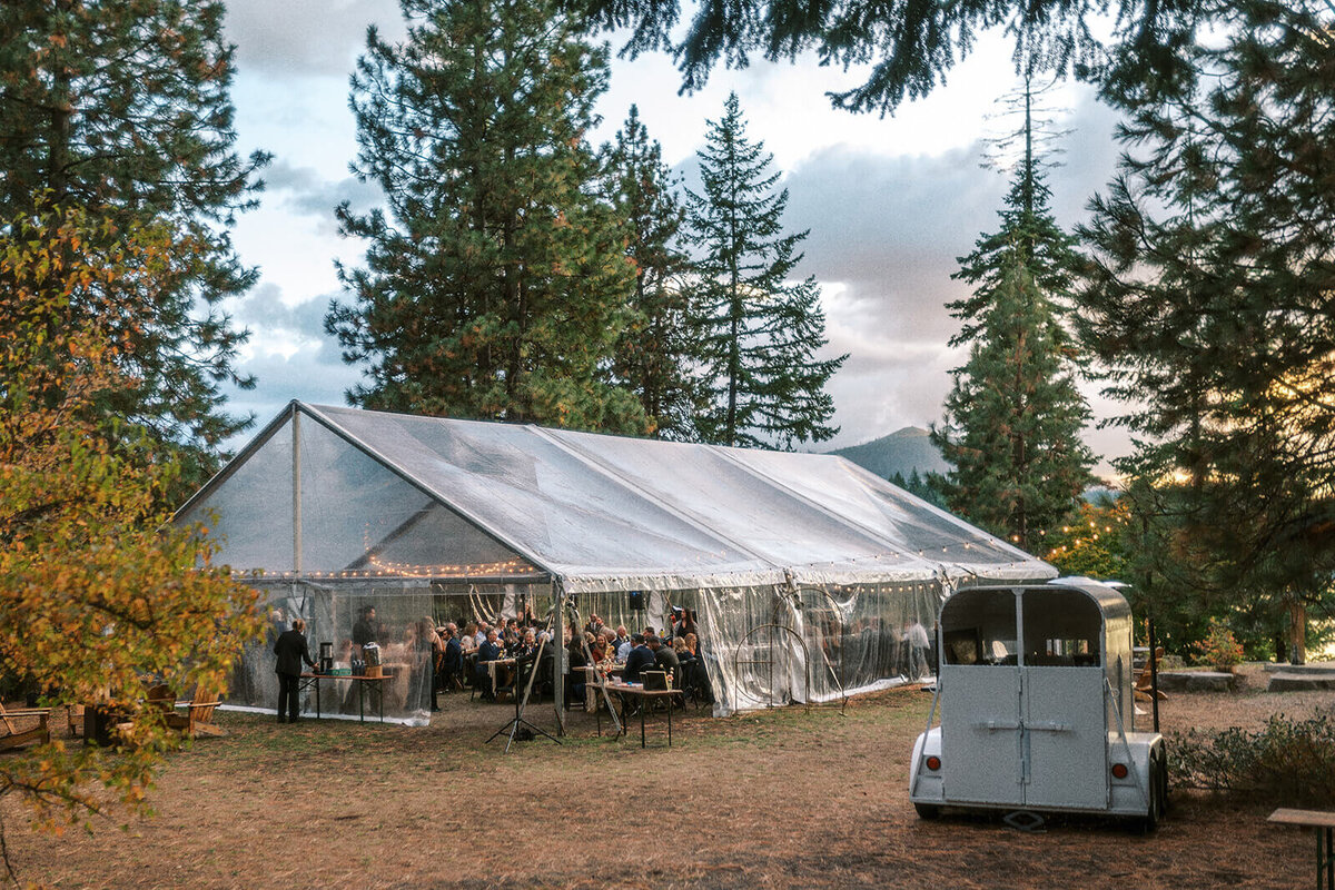 A clear wedding reception tent outdoors surrounding by tall trees at Suttle Lake Lodge in Oregon.
