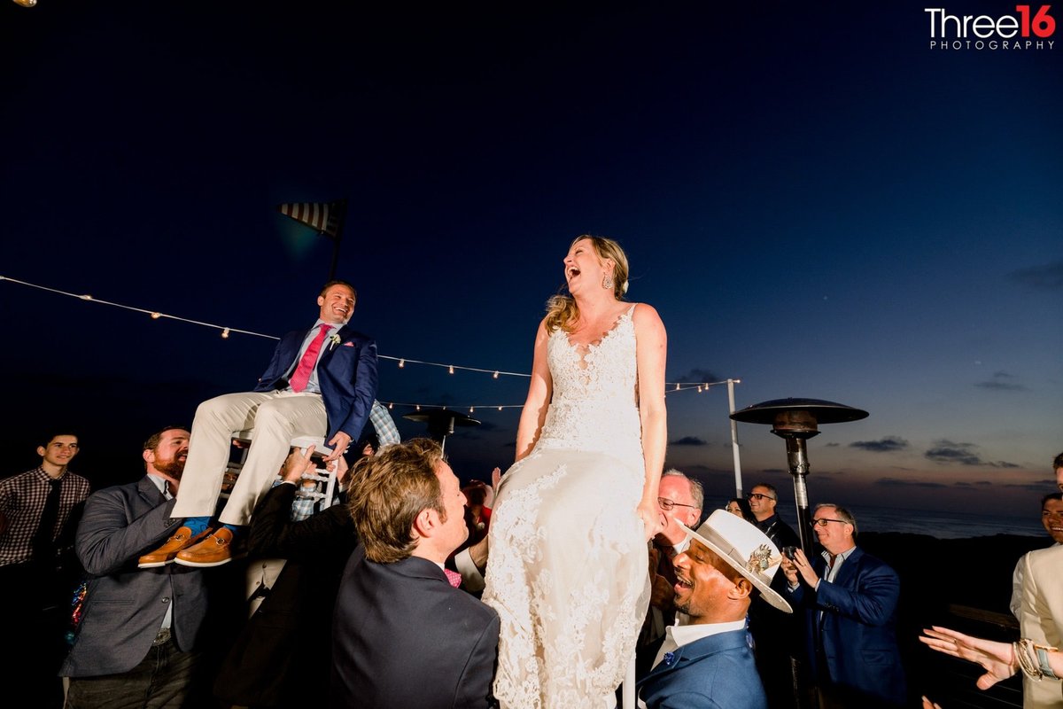 Bride and Groom are lifted up in their seats at evening wedding reception