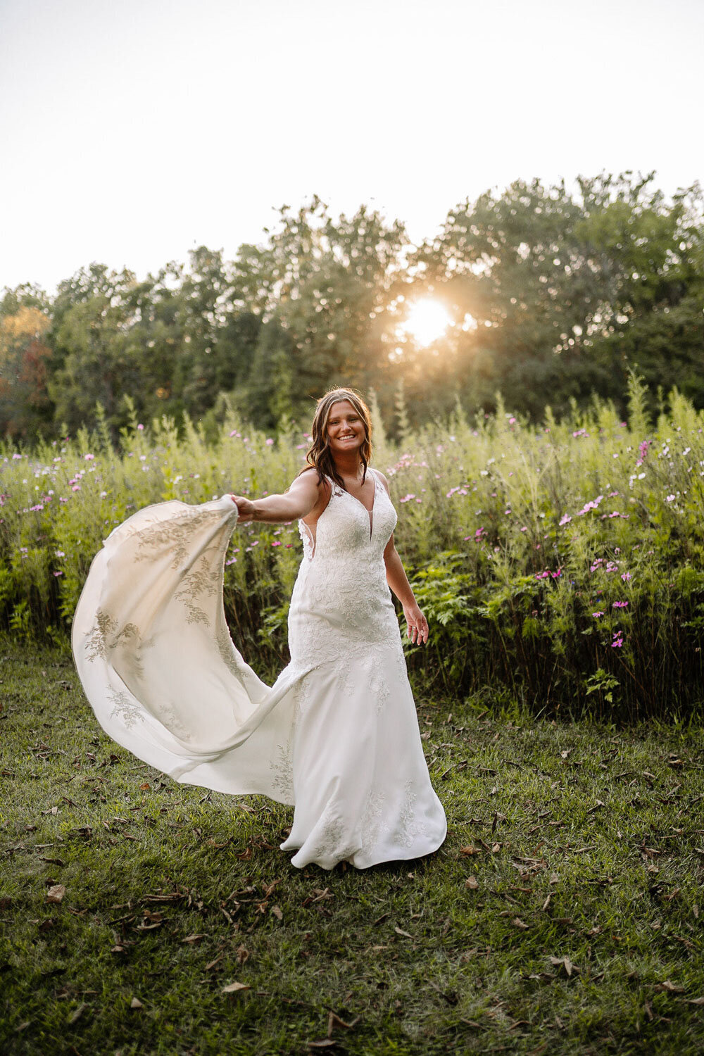 Bride twirling in her wedding gown with sunlight streaming through trees