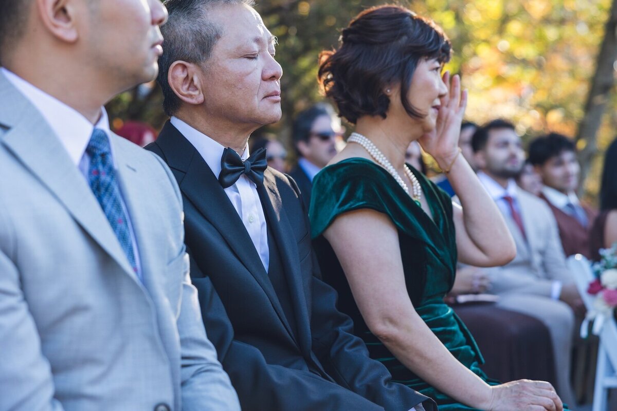 Guests seated at the outdoor ceremony, crying.