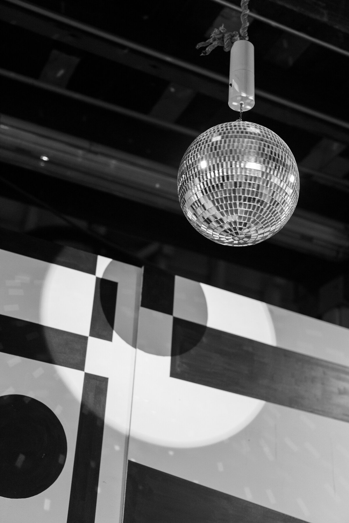 Disco ball hangs in front of black and white geometric background