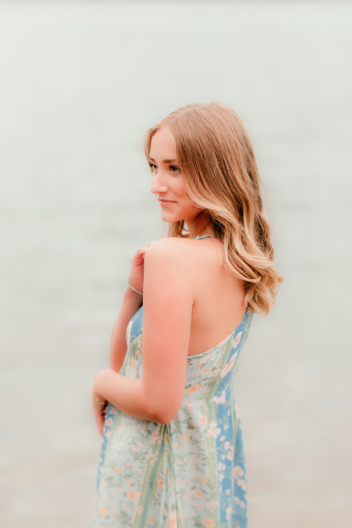 Outdoor senior photo of teen girl with long hair posing in open grassy field during sunset in Minnesota.