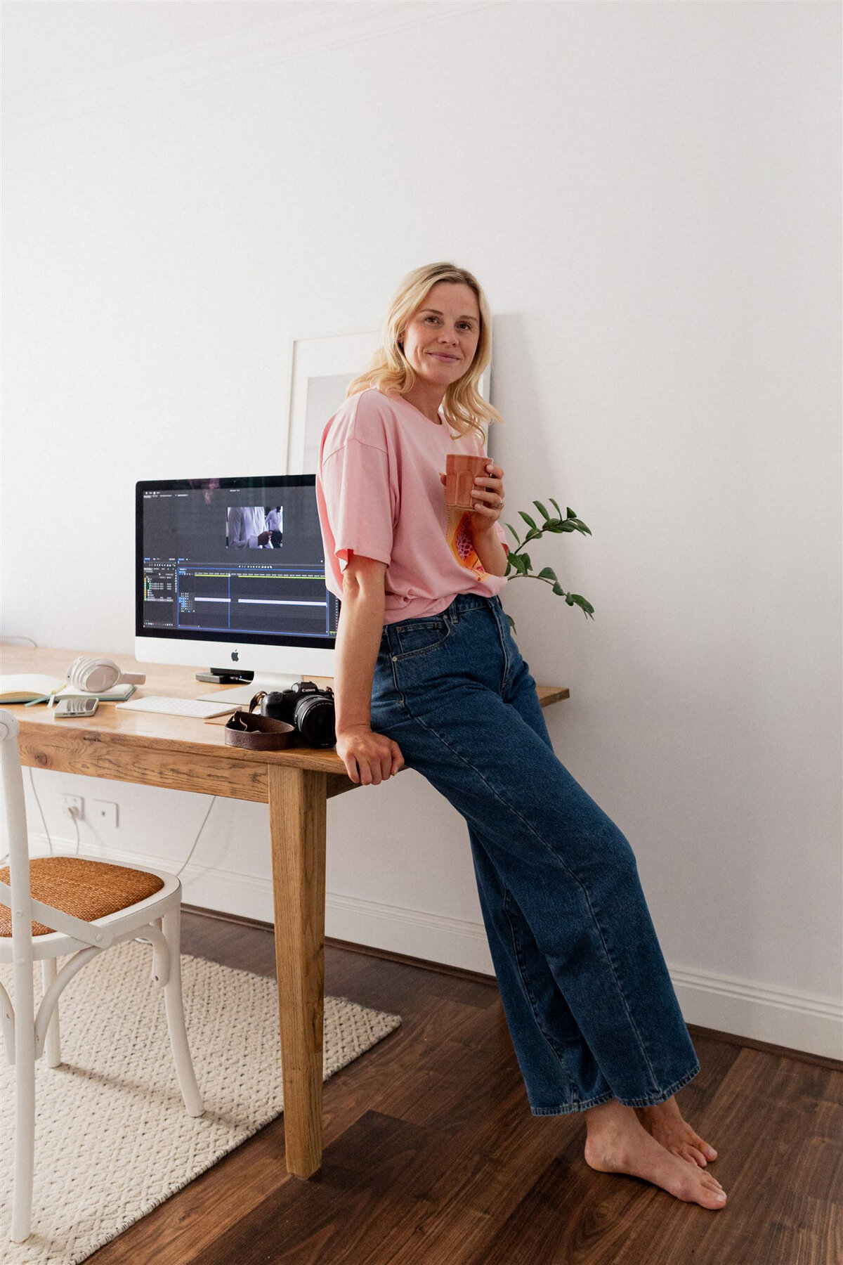 Jessie standing in her home office, holding a coffee and smiling at the camera.