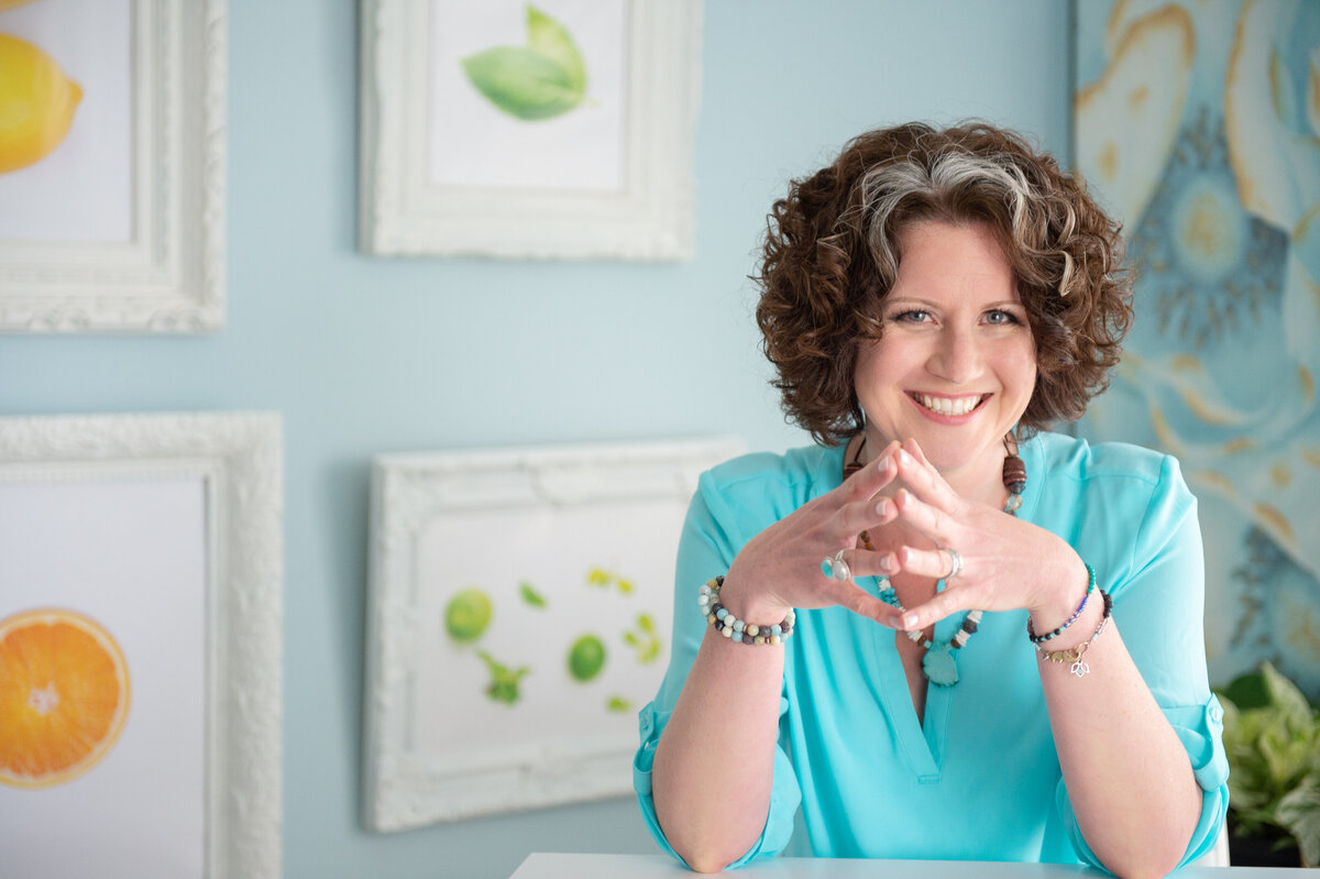an Ottawa branding photo of a nutritionist in her home office wearing a blue shirt and smiling.  Captured by JEMMAN Photography Commercial