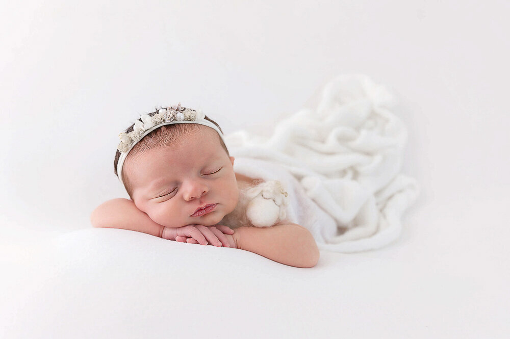 baby girl with all white setup for her newborn photography session in Hamilton, Ontario.