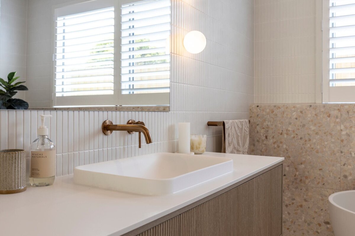 Modern bathroom with pink terrazo tile and brass taps