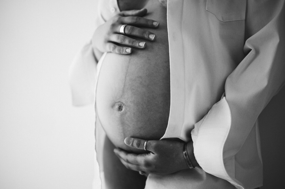 Pregnant belly lovingly held in a black-and-white photo