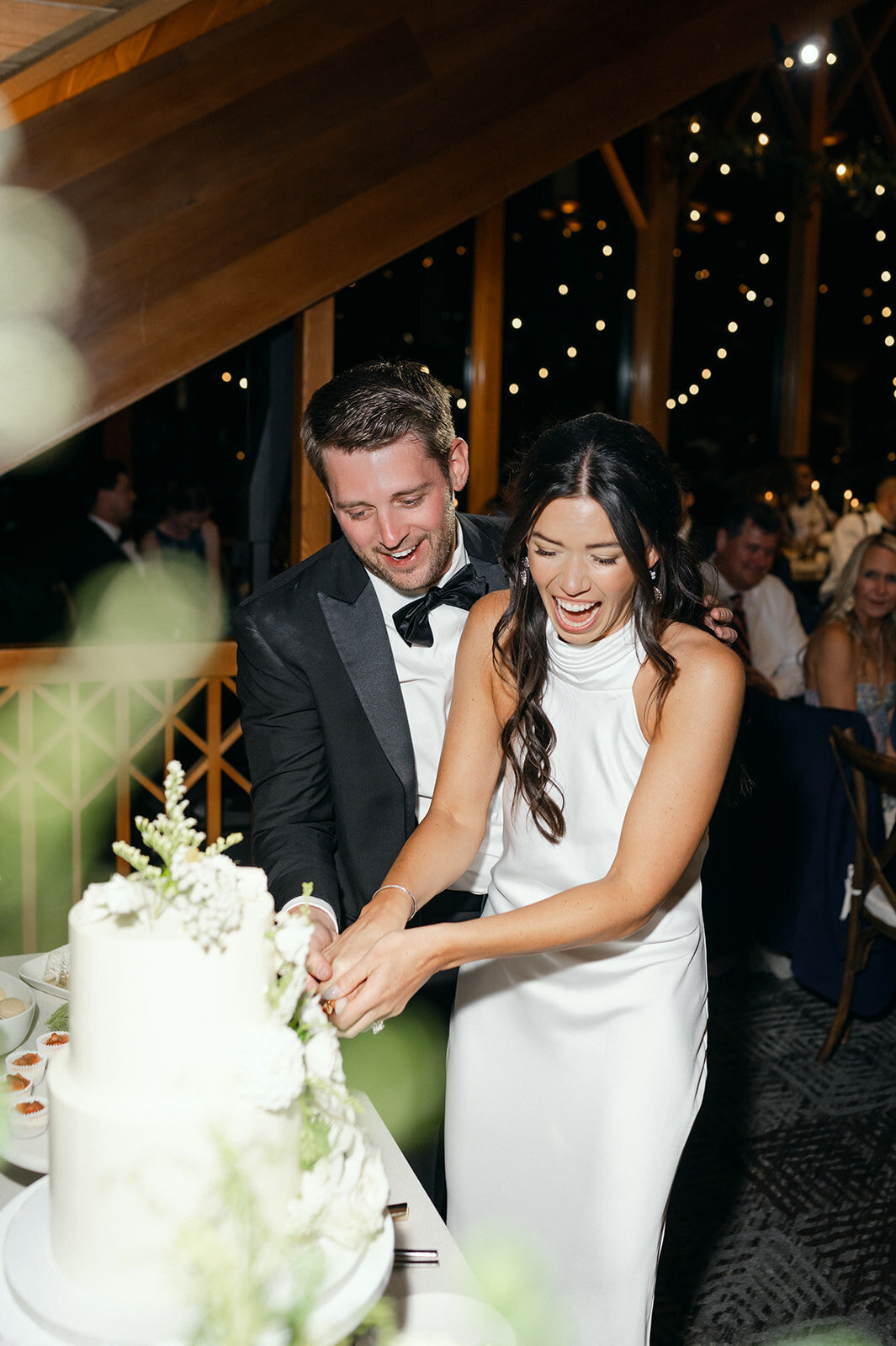 Bride and Groom smiling while cutting their wedding cake at Edgewood Tahoe Resort.