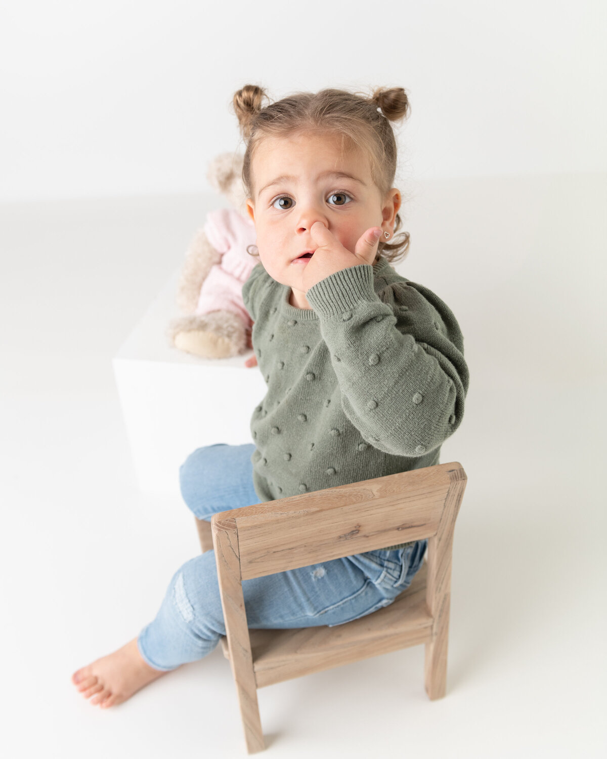 Milestone studio portrait of a toddler girl beside her teddy, captured in a quiet moment of wonder and comfort.