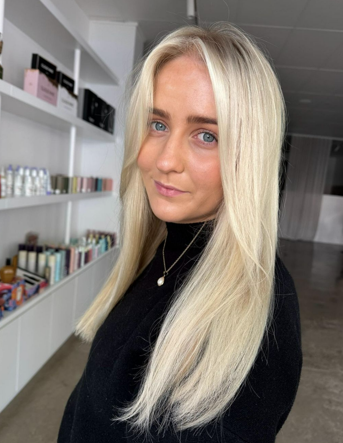 Girl with green eyes looking into camera with long blonde shiny hair