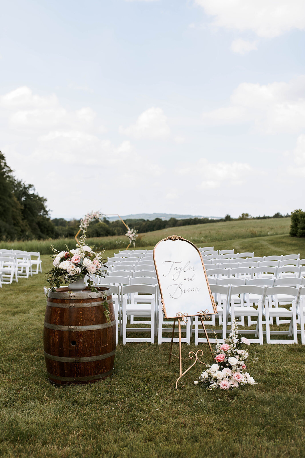 outdoor wedding ceremony in upstate new york with barrel aisle caps and mirror welcome sign