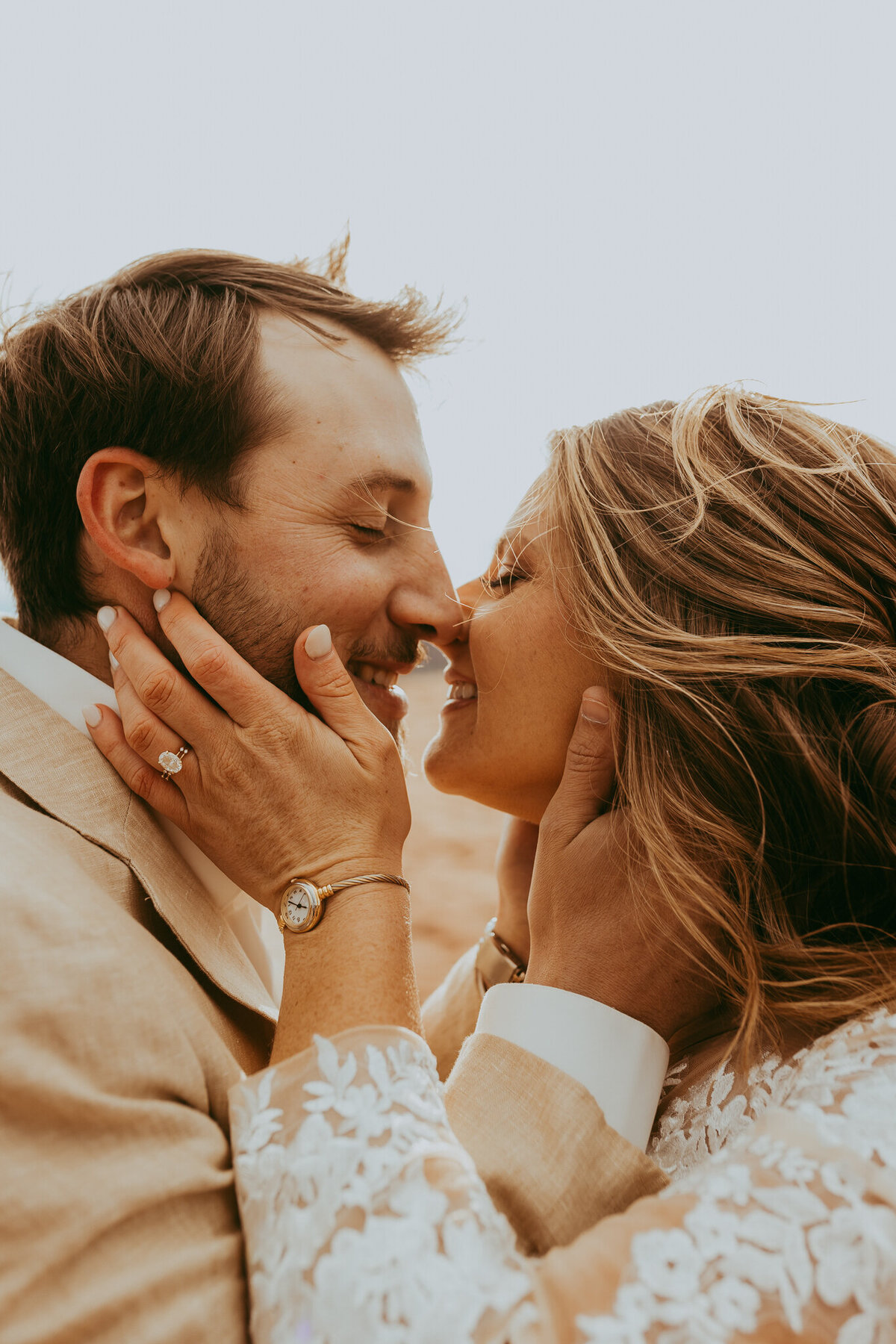 couple smiles as they kiss in bridal attire