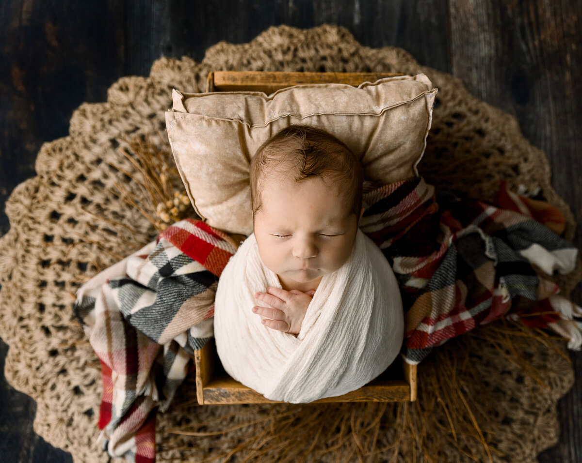 Newborn baby boy wrapped and posed on a plaid blanket