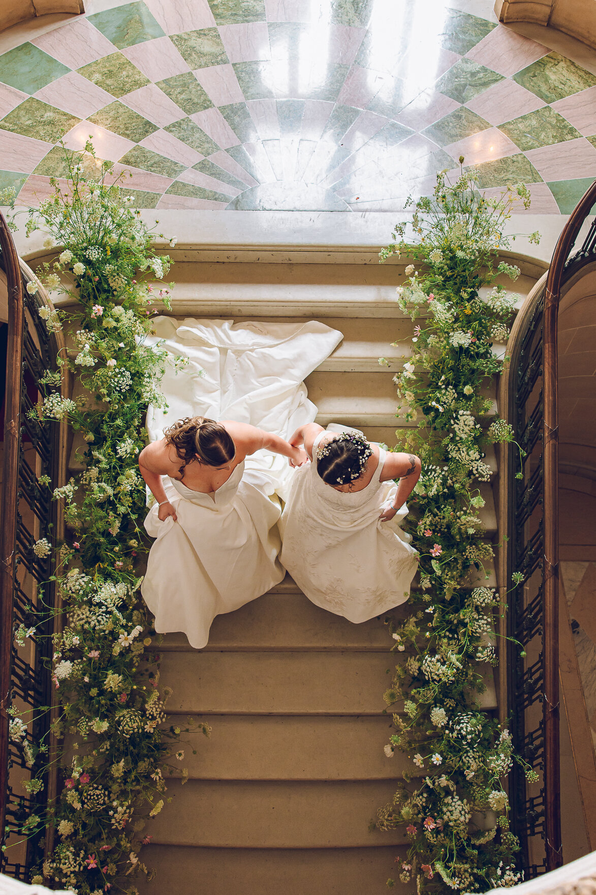 A queer couple descends the grand staircase at Armour House in Lake Forest