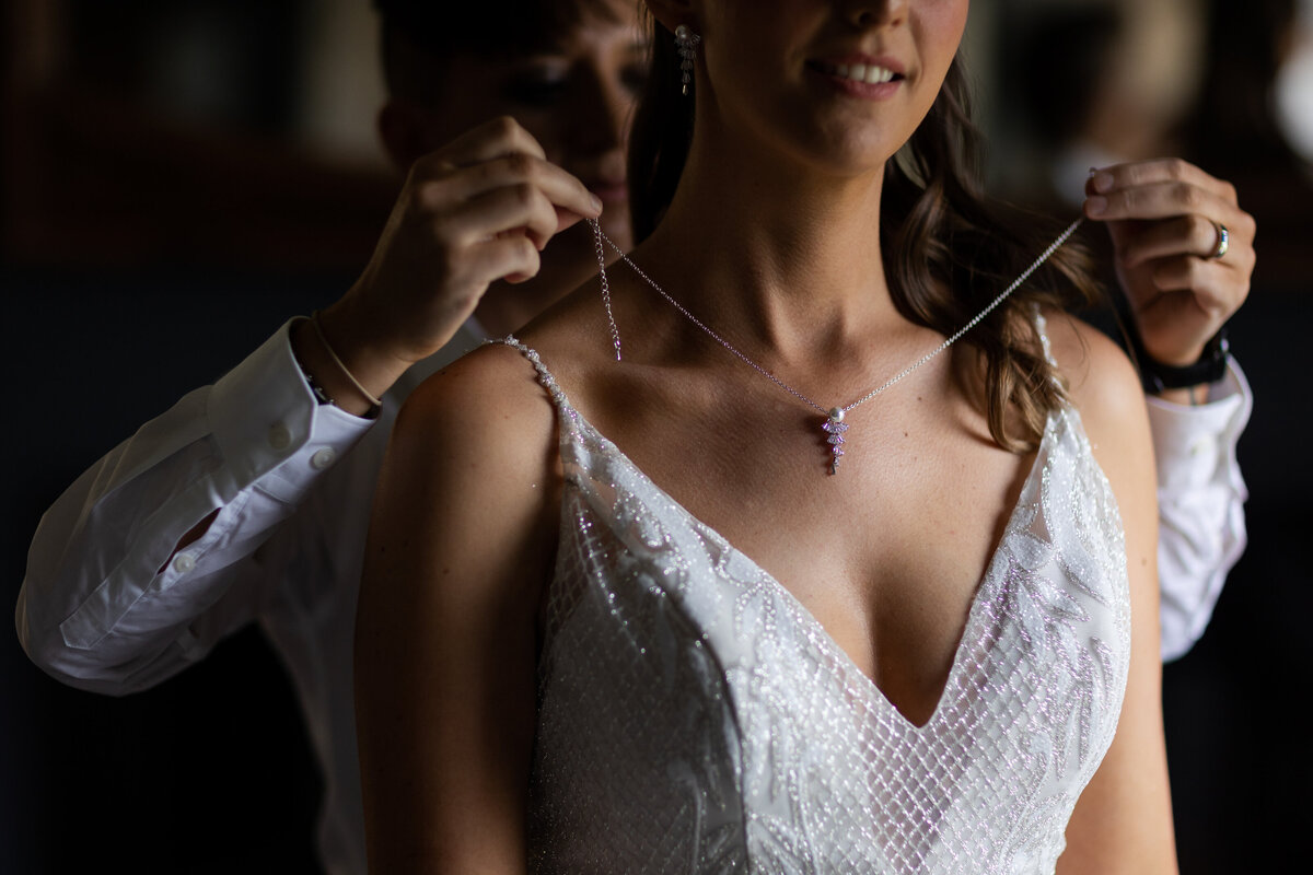 Brides necklace being put on her neck on her wedding day.