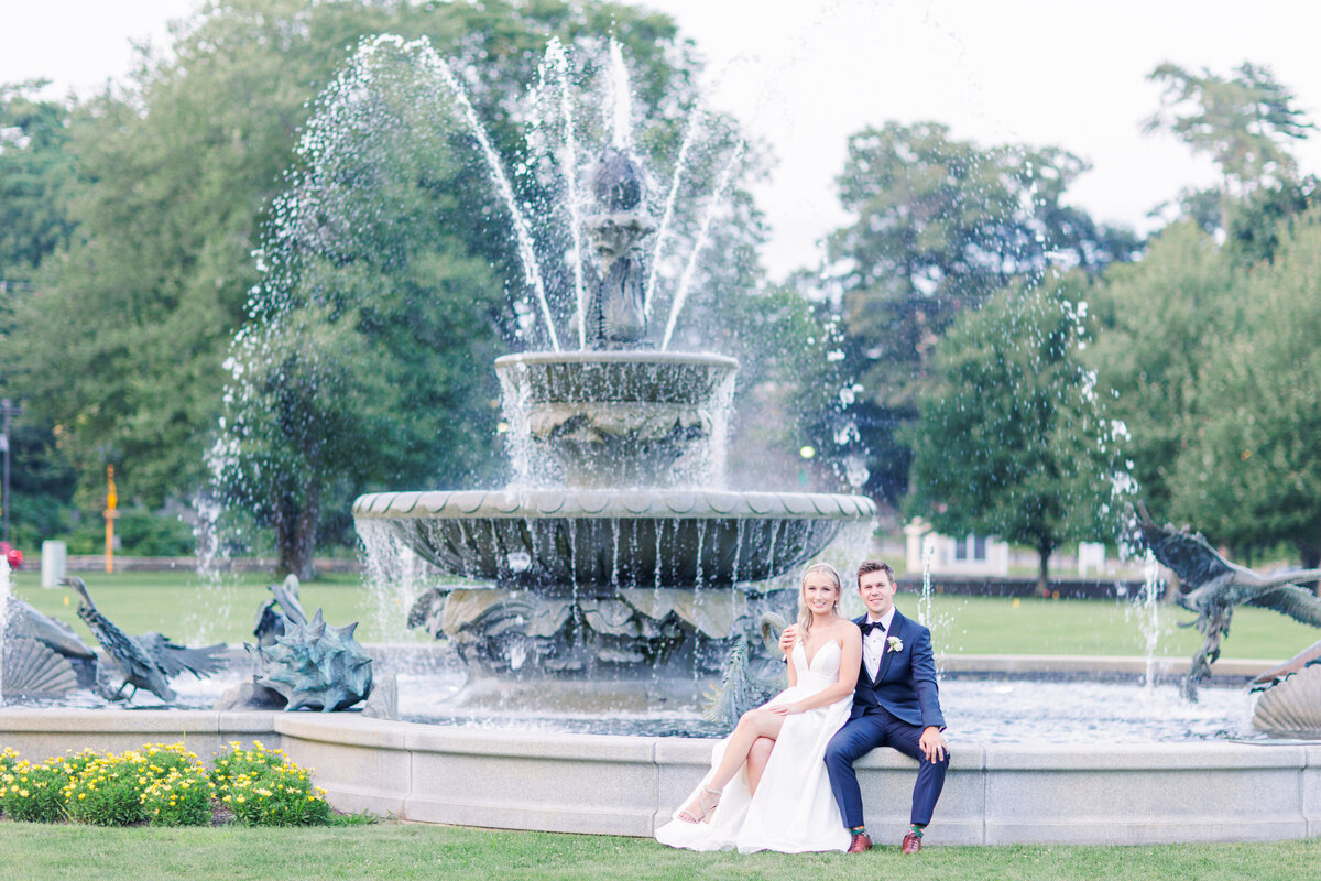 Bride and groom sitting on a fountain and staring at the camera representing editorial Boston wedding photography