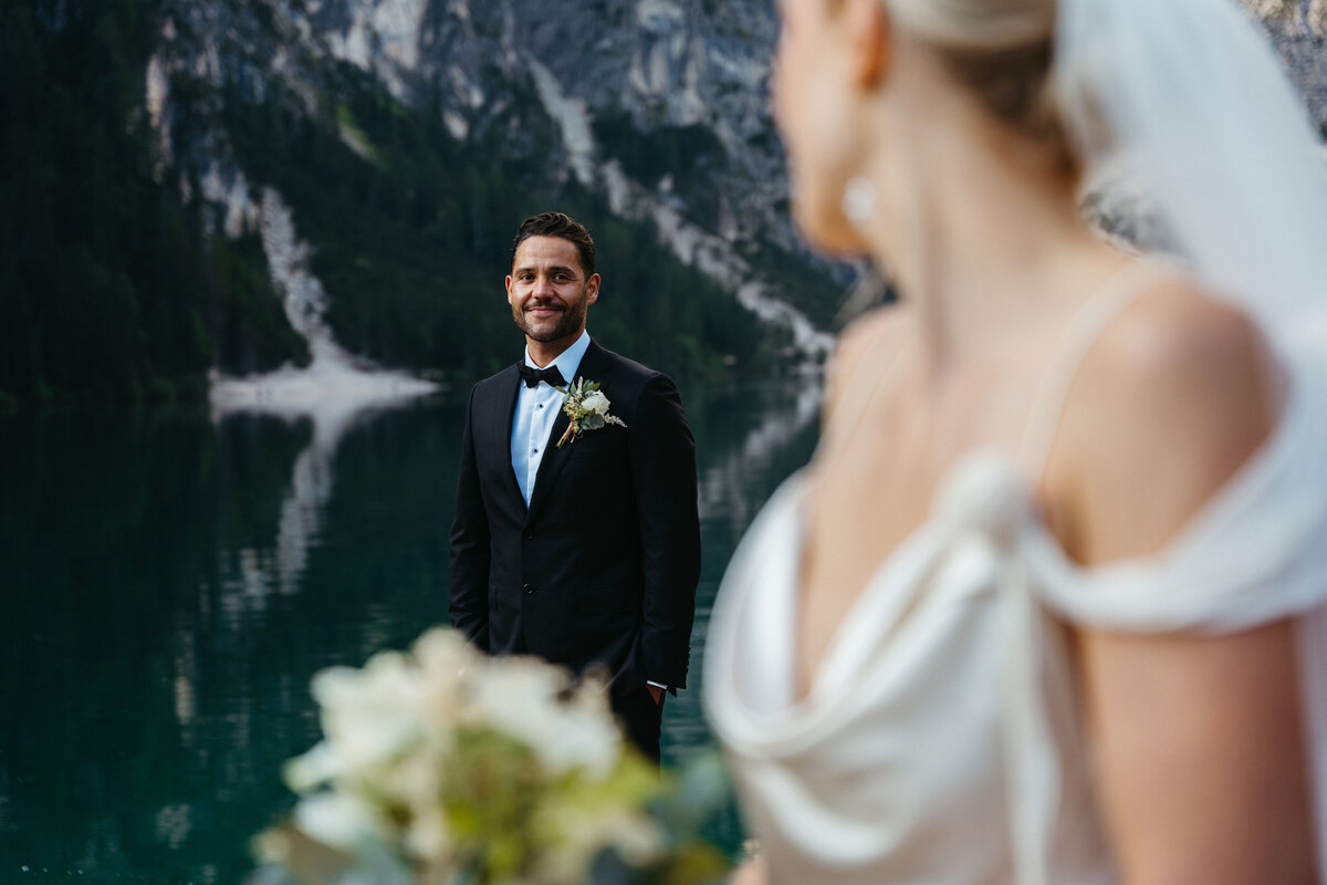 Bride and groom looking at each other on lakeside dock