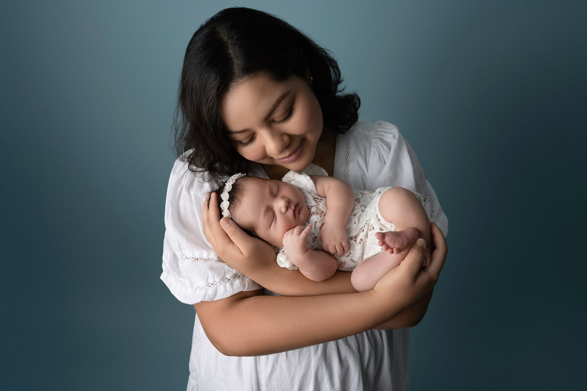 Mother holding newborn baby white dress Austin professional family photographer