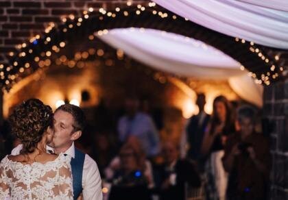 A bride and groom share a kiss at their wedding reception