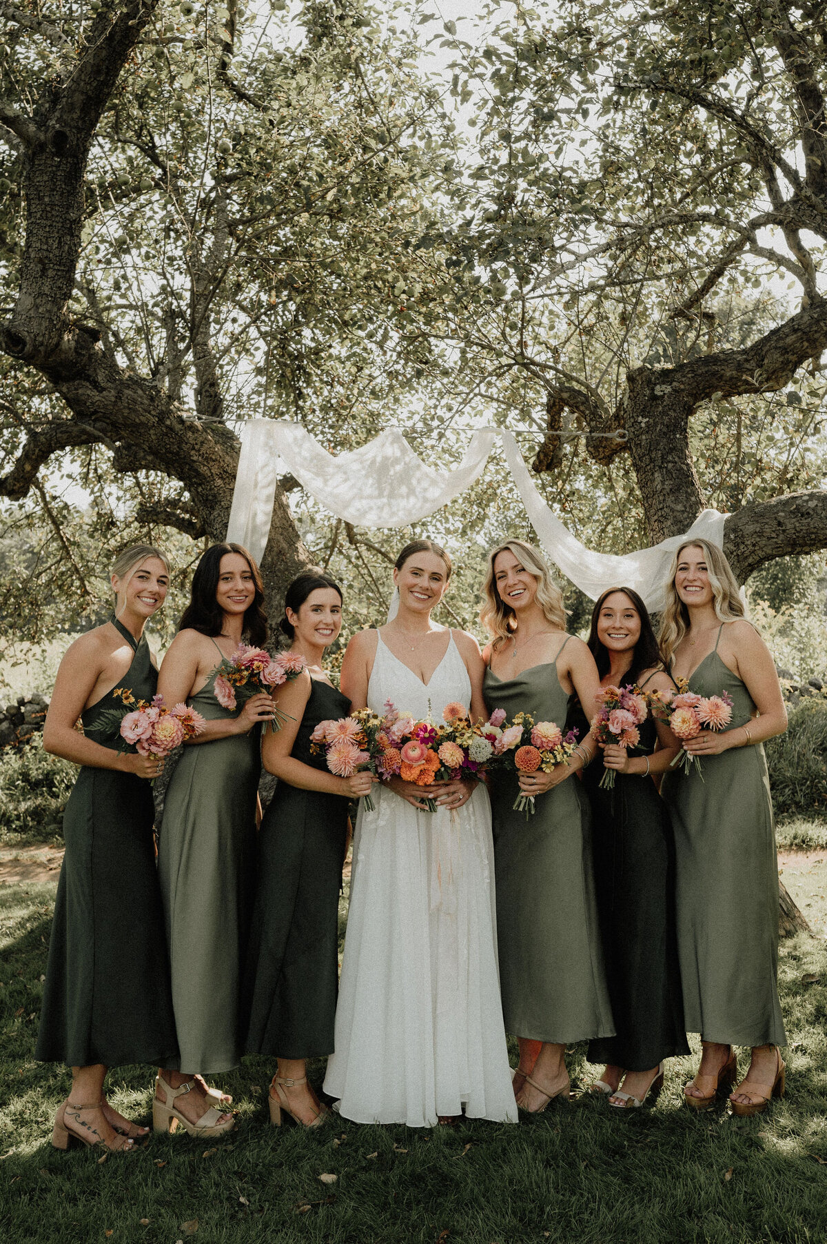 Bride and bridesmaids smiling with bouquets
