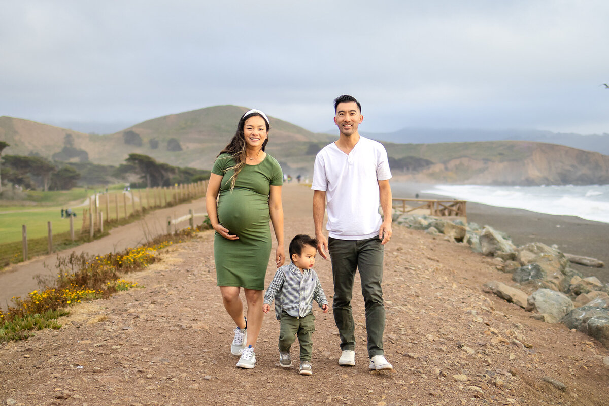 Bay Area Maternity Portfolio - Ellobelle Photography featuring a family walking along a scenic coastal trail during golden hour maternity session